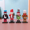 A row of four wooden nutcracker soldier ornaments in various colors and outfits standing on a pink surface.