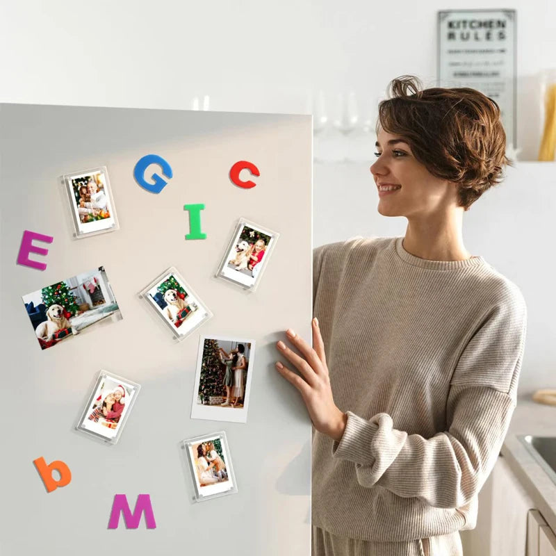 A woman displays a collection of colorful magnetic photo frames on a light gray wall.