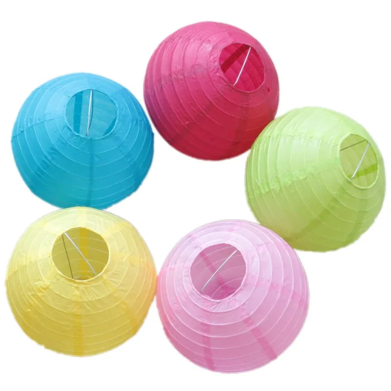 A collection of five round paper lanterns in shades of pink, blue, green, and yellow.