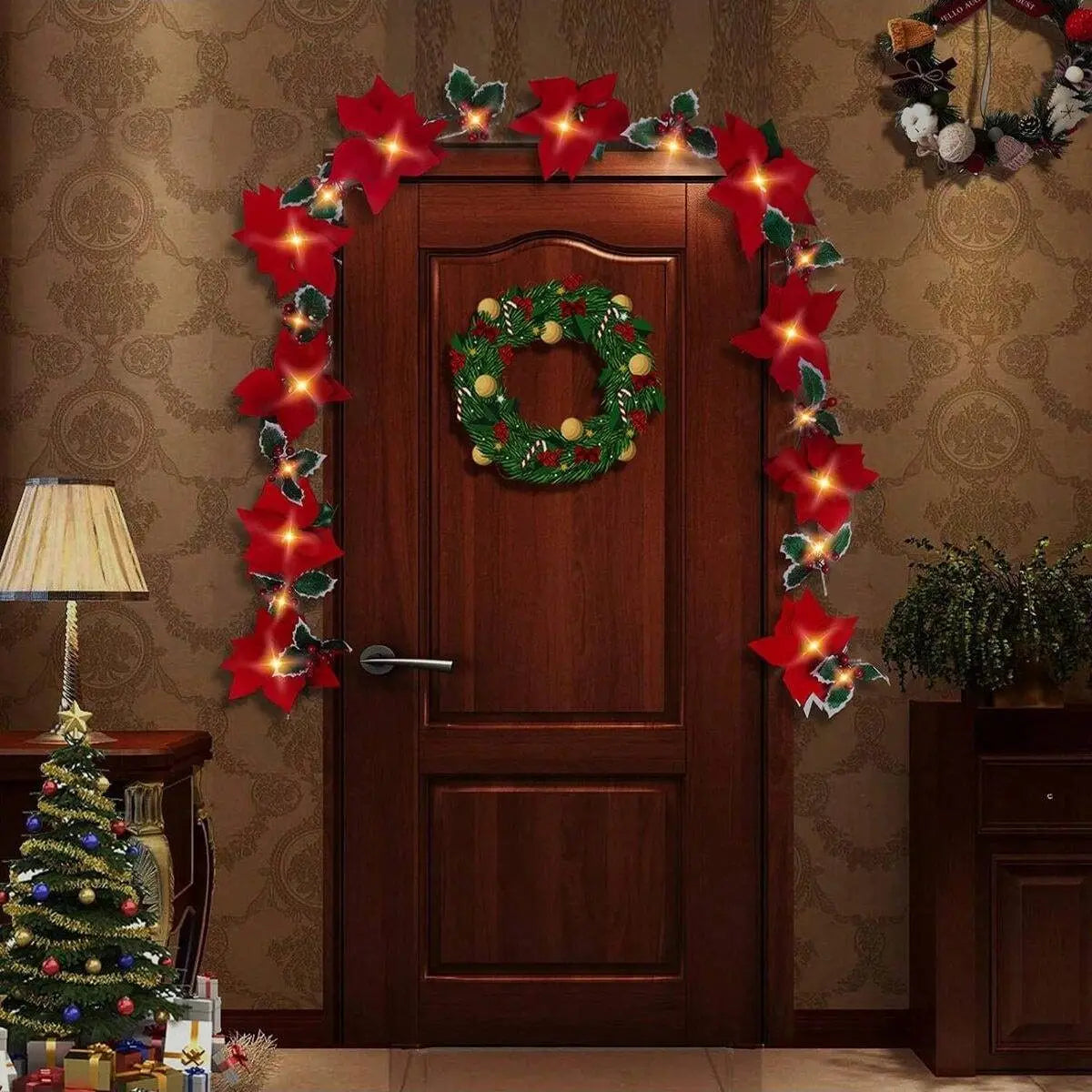 A wooden door decorated with red poinsettia garland lights and a green wreath on a textured wall.