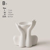 A white ceramic figural vase shaped like an artistic human form.