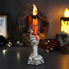 Gruselige Geisthand hält eine orange LED-Kerze mit flackernder Flamme für Halloween-Dekoration.