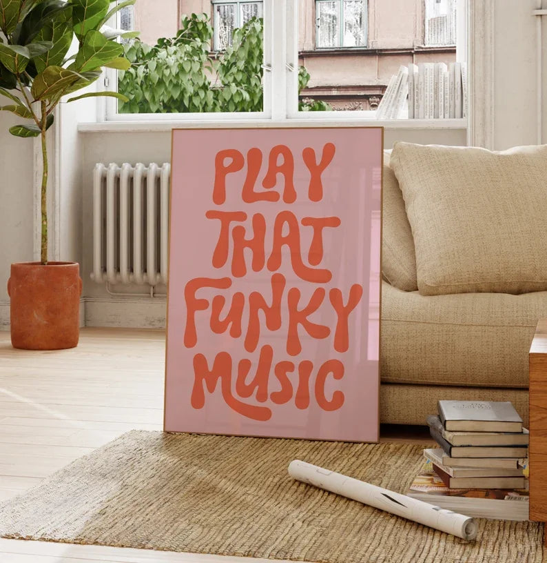 A pink canvas art poster with the text PLAY THAT FUNKY MUSIC in orange lettering displayed indoors.