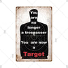 A vintage metal warning sign plaque with text that reads You are no longer a trespasser You are now a Target