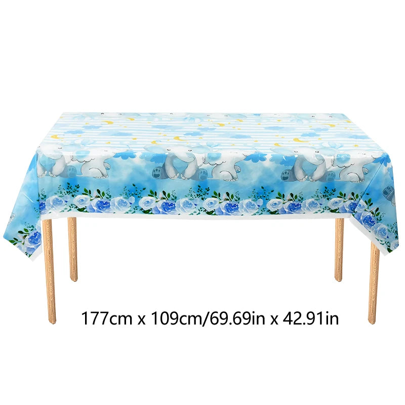 A light blue tablecloth decorated with cartoon elephants and blue clouds for a party setting.