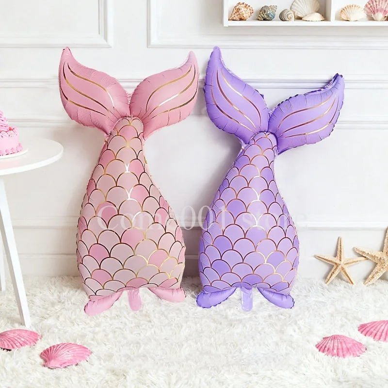 A set of pink and purple foil balloons shaped like a mermaid tail and dolphin, decorated with scales and seashells.