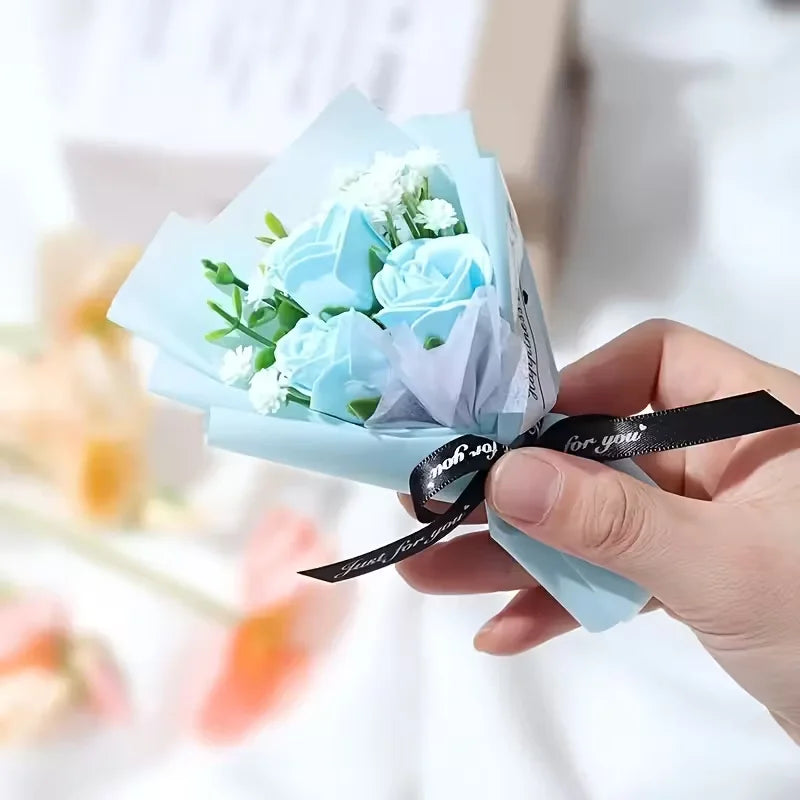 Une main tient un bouquet de mini roses artificielles bleu clair avec des fleurs de remplissage blanches et un ruban noir.