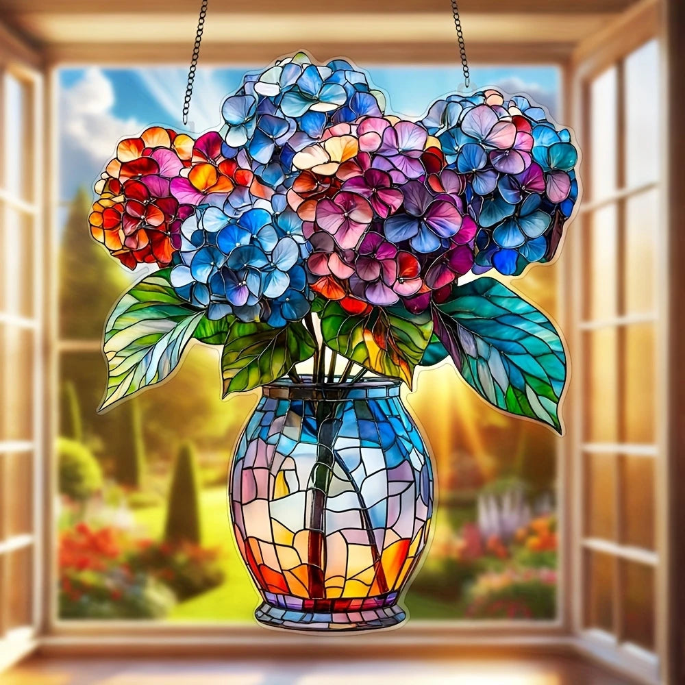 A colorful acrylic floral pendant with a chain hangs in front of a window displaying a garden view.