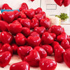 A close-up of red heart-shaped latex balloons arranged on a surface for party decoration.