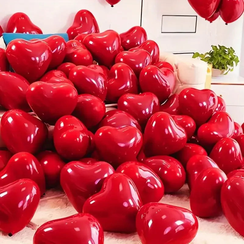 A close-up of red heart-shaped latex balloons arranged on a surface for party decoration.