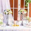 A silver crystal flower centerpiece stand with pink and white flowers and a candle holder on a white tablecloth.