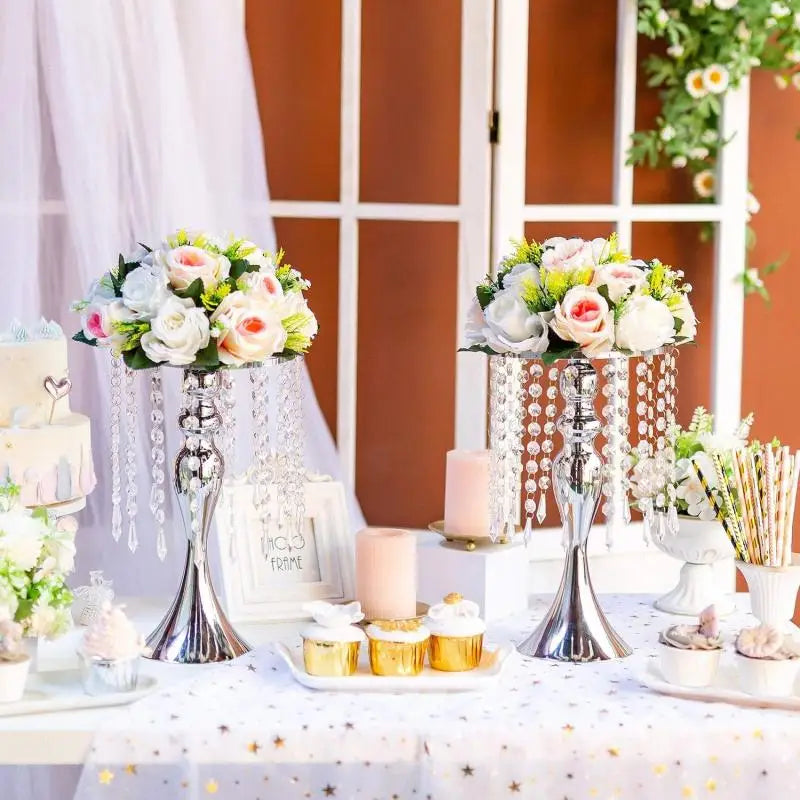 A silver crystal flower centerpiece stand with pink and white flowers and a candle holder on a white tablecloth.