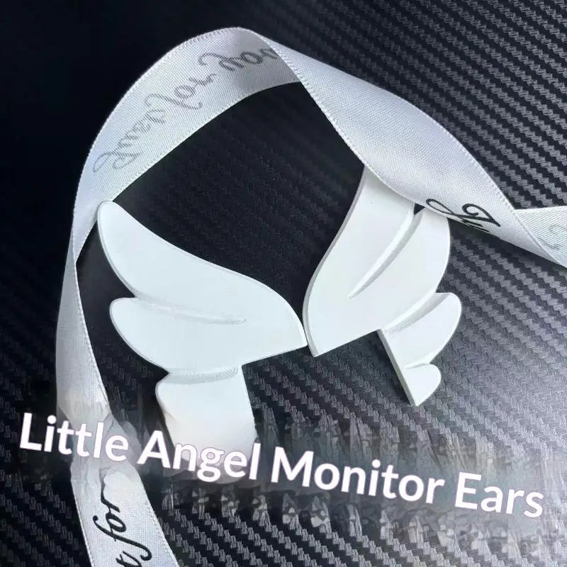 A pair of white monitor wing decorations with a ribbon, displayed against a dark background.