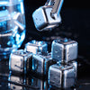 Close-up of reusable stainless steel ice cubes dripping water on a dark surface.