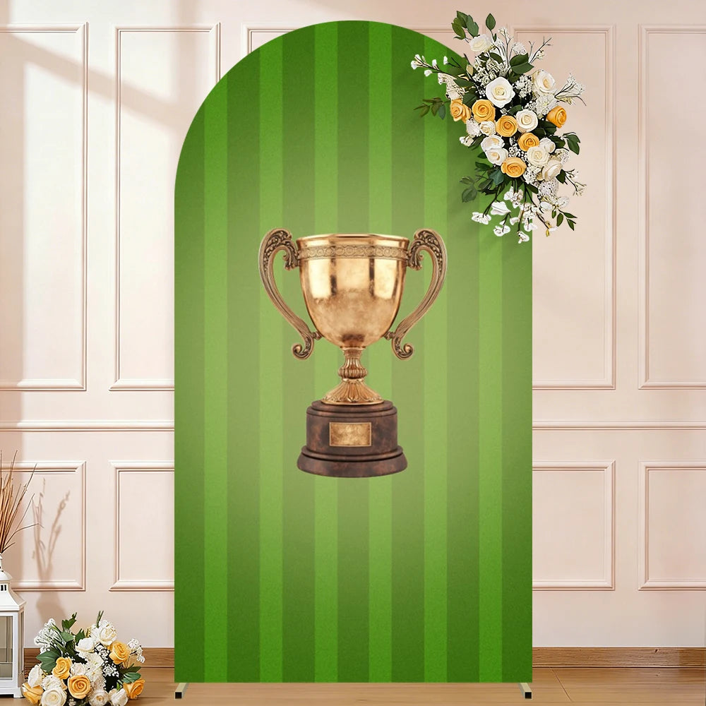 A golden trophy is centered on a green striped arch backdrop for a party photo booth.
