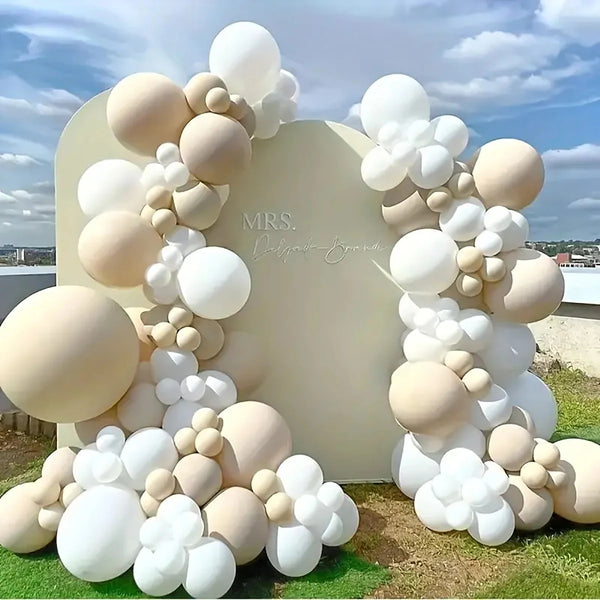 A large balloon garland arch made of white and beige latex balloons set up for an event backdrop.