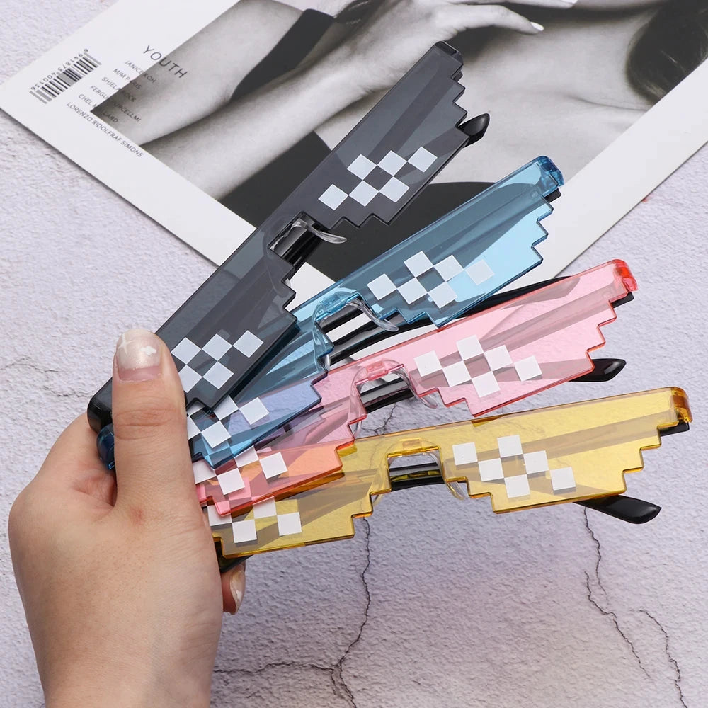 A hand holds a pair of pixel mosaic sunglasses with retro digital-style frames and UV400 protection.