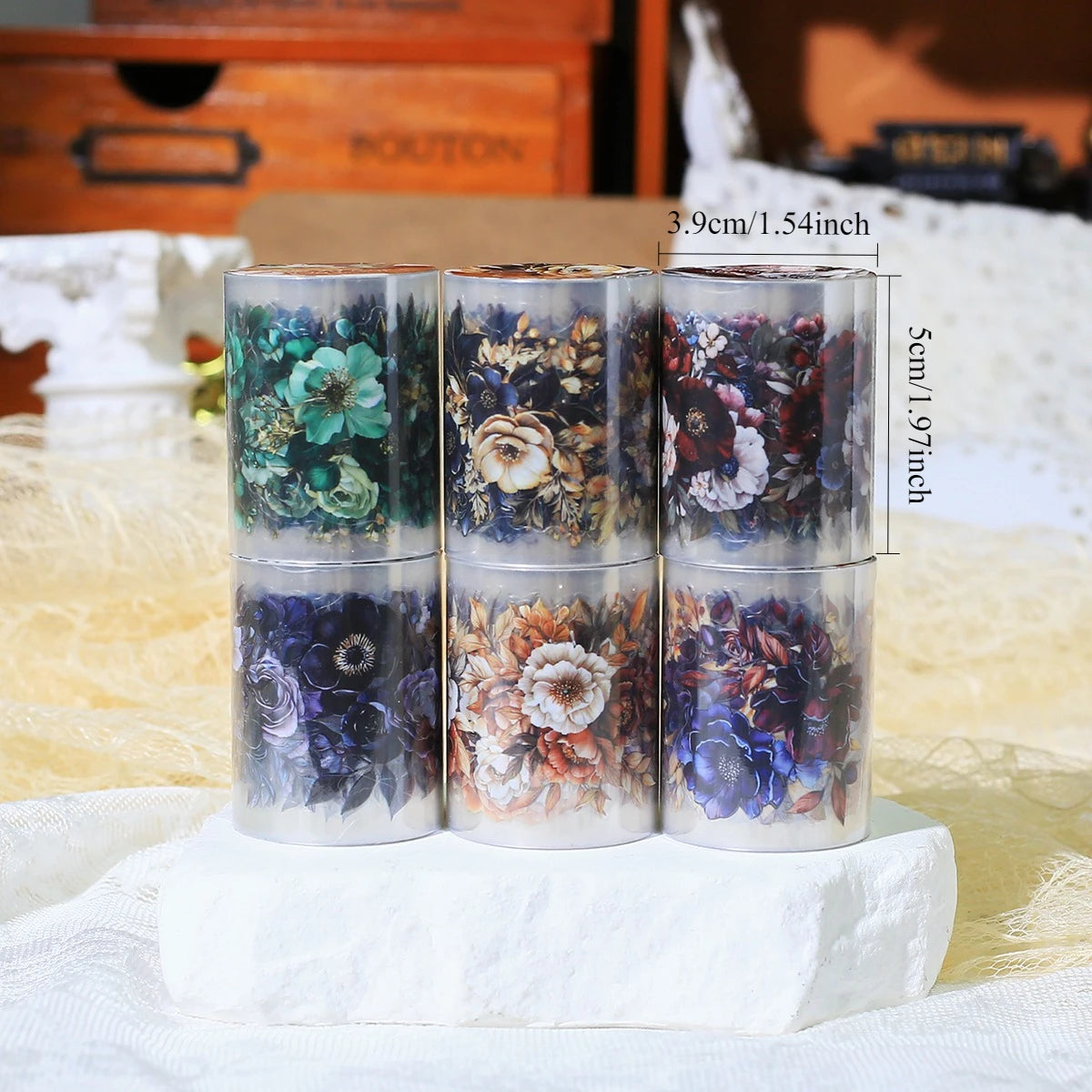 Three glass rolls of floral PET stickers with measurements displayed on a white surface.