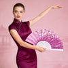 A woman in a purple dress holds an open pink and white folding fan.