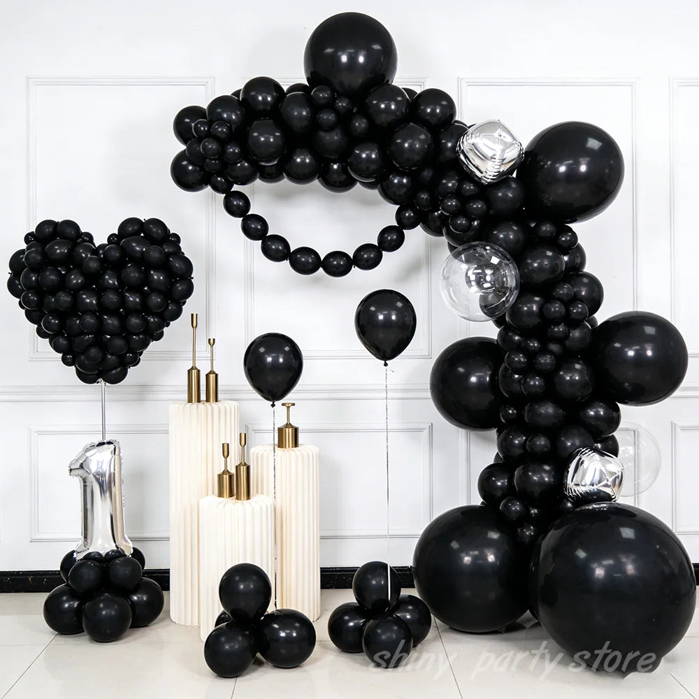 A cluster of black latex balloons arranged in heart shapes and clusters for parties and celebrations.