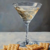 A glass of iced tea in a martini glass sits on a white surface with crackers nearby.