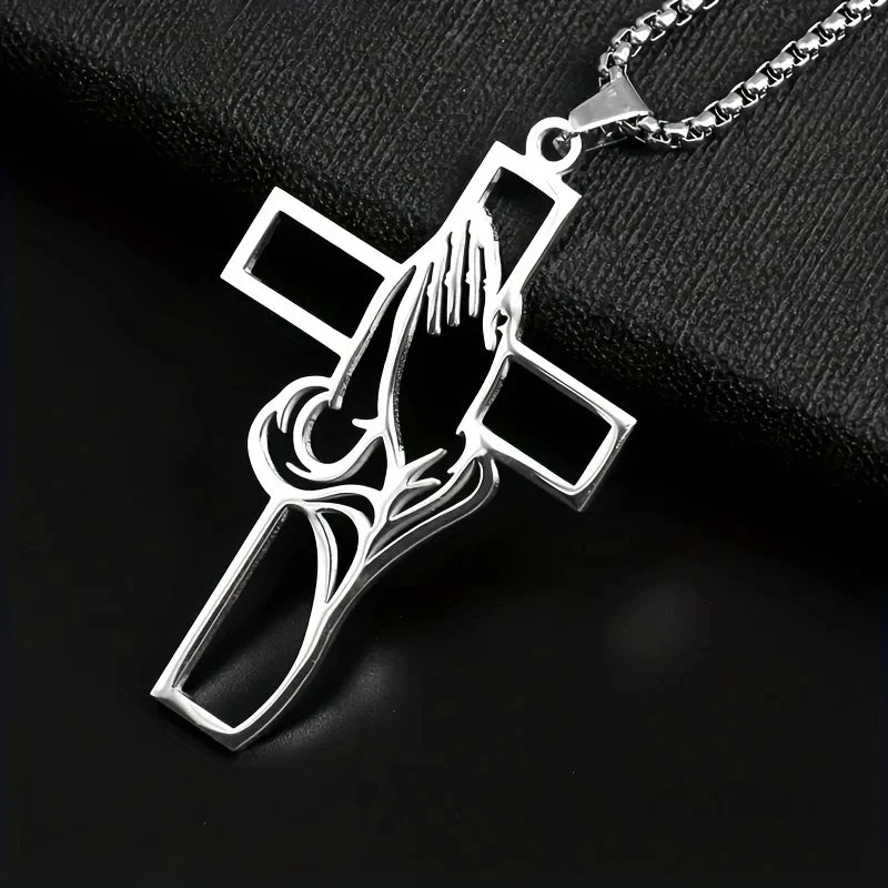 Silver pendant featuring a detailed design of prayer hands within a cross shape on a chain.