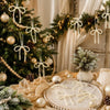 Elegant pearl bow Christmas tree ornaments and hanging decorations displayed on a rustic wooden background.