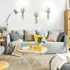 A living room wall decorated with three metal vases holding dried flowers and a light blue lamp.