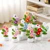 A collection of hand-woven crochet flowers in various colors potted in white ceramic containers.