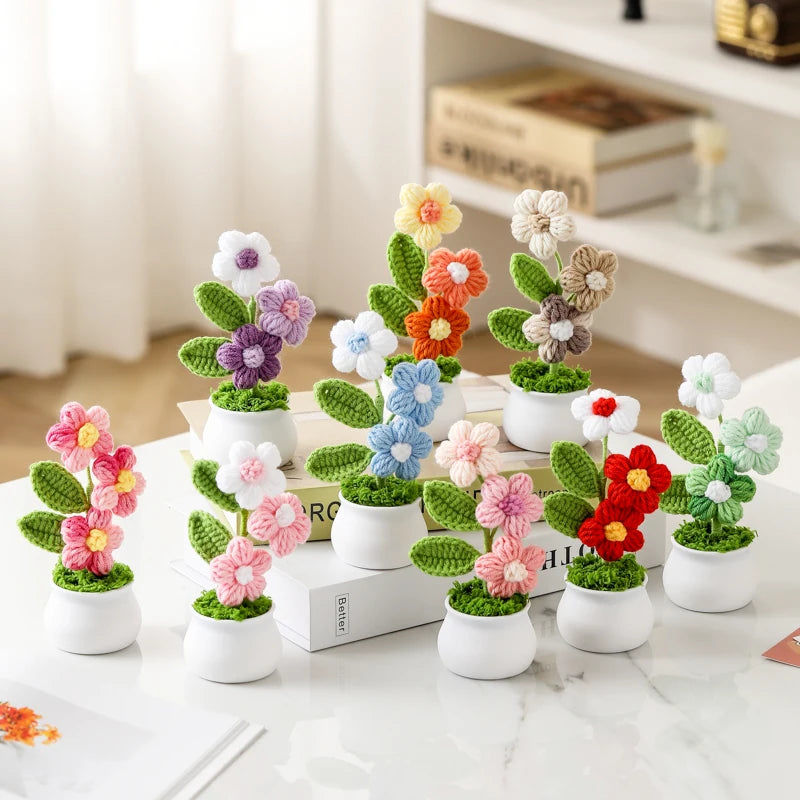 A collection of hand-woven crochet flowers in various colors potted in white ceramic containers.