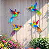 Colorful metal hummingbird wall art featuring vibrant iridescent feathers displayed on a light wooden fence.