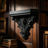 A dark wooden wall shelf featuring an ornate Gothic carving with intricate foliage details.