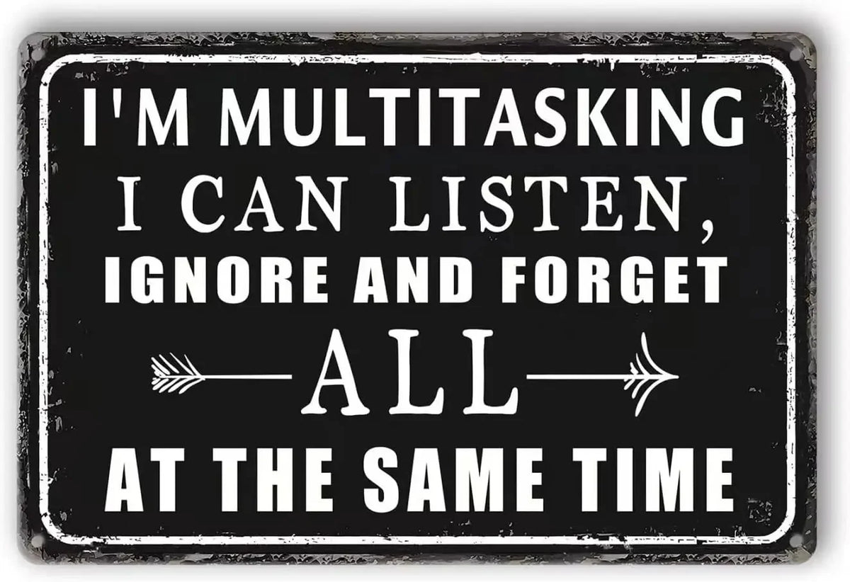 A black rectangular metal sign with white text that reads I'M MULTITASKING I CAN LISTEN IGNORE AND FORGET ALL AT THE SAME TIM