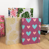 A collection of linen printed photo albums in pink, green, and floral patterns.