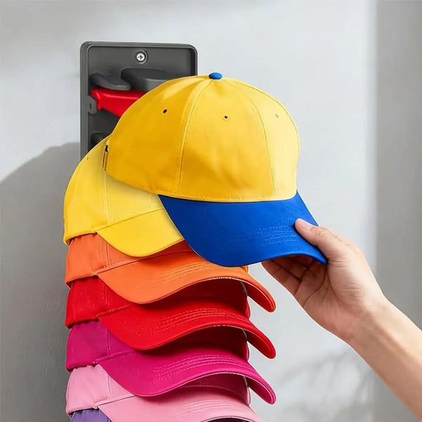 A hand is pulling out a stack of colorful hats from a wall-mounted organizer with spring clips.