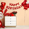 Red star and heart foil balloon decoration set with letters spelling happy birthday on a wall