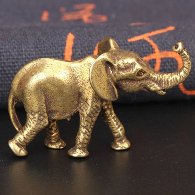 Antique bronze elephant figurine with a textured finish standing on a dark surface.