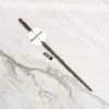 A long, dark metal wand replica with a labeled metal core is displayed on a white marble surface.