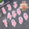 Glitter number cake candles from 0 to 9 with pink bows arranged on a gray surface.