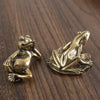 Antique brass frog sculpture decor resting on a dark wooden surface.