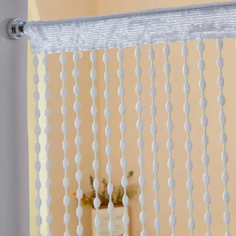 Silver beaded string curtain with white tassels used as a bohemian door and window drape.