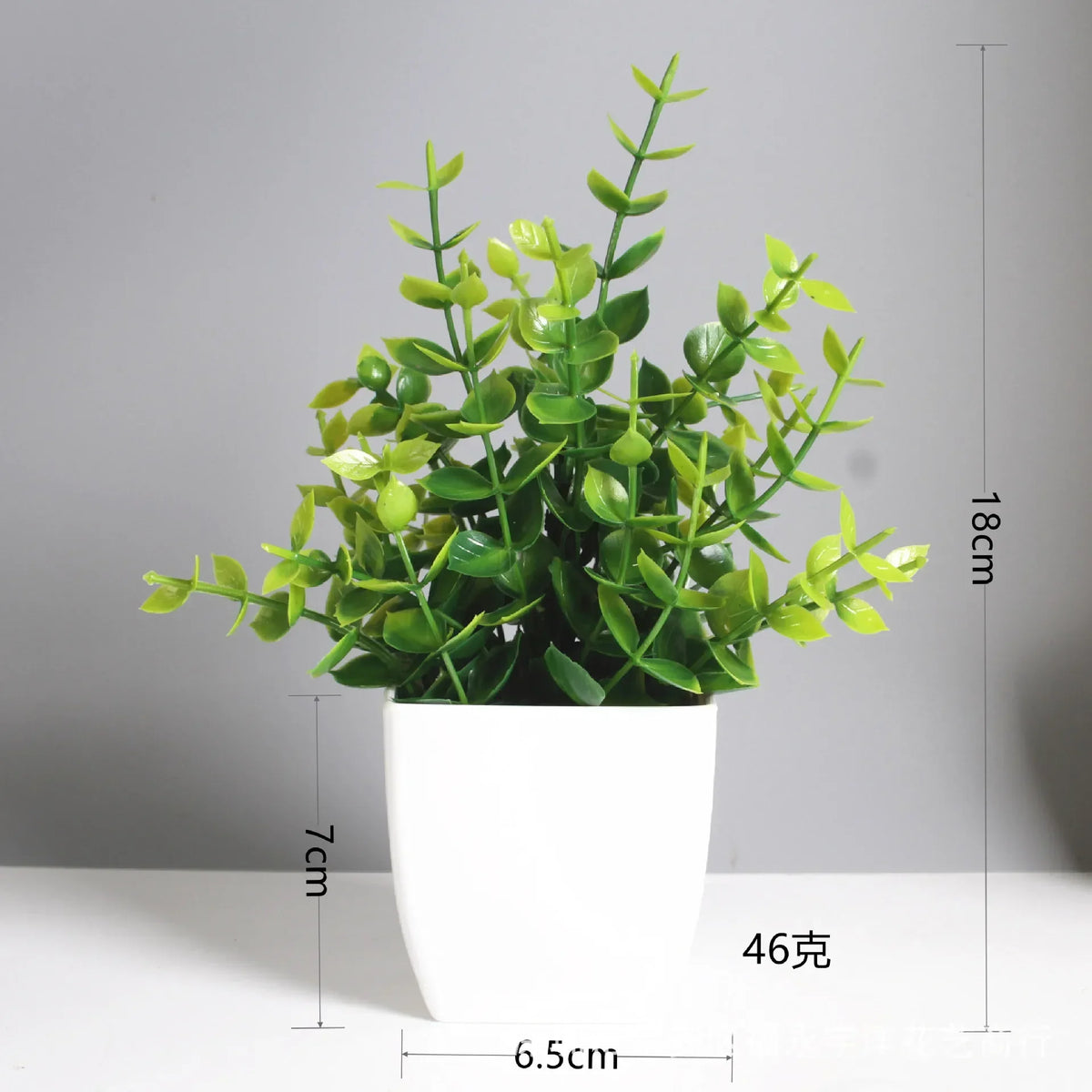A potted artificial bonsai plant with bright green leaves and yellow accents, shown against a light gray background.