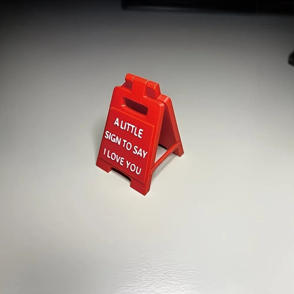 A red 3D printed letter sign ornament shaped like a house, with the text A LITTLE SIGN TO SAY I LOVE YOU engraved on it.