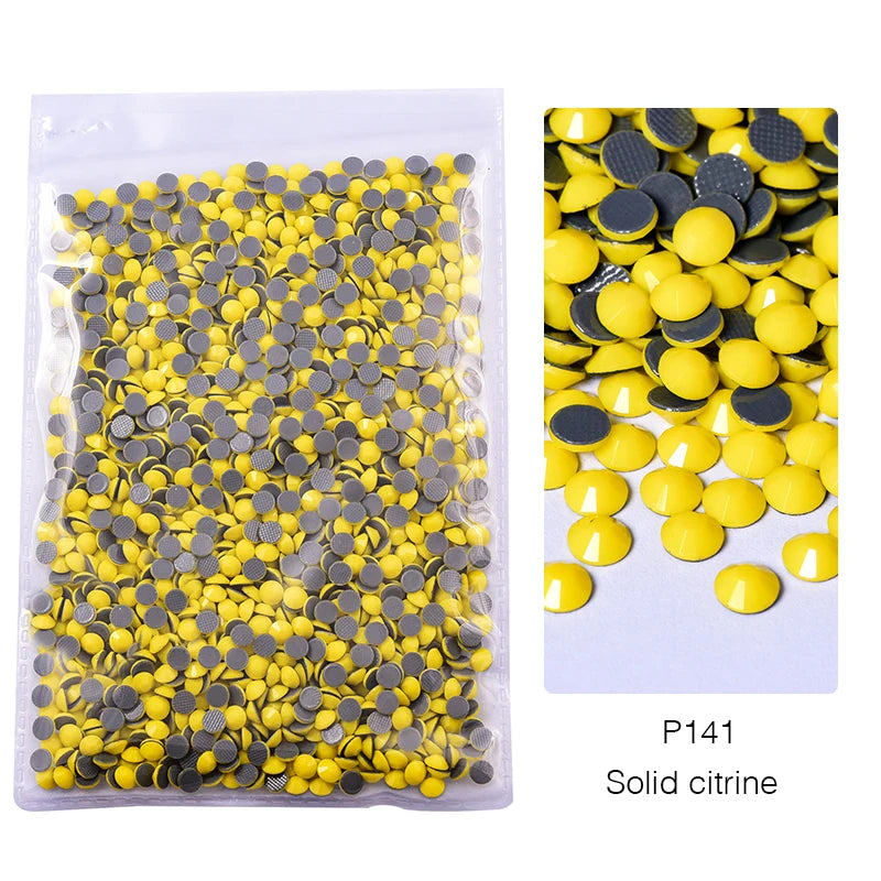 A clear plastic bag filled with mixed yellow and silver solid citrine glass rhinestones.