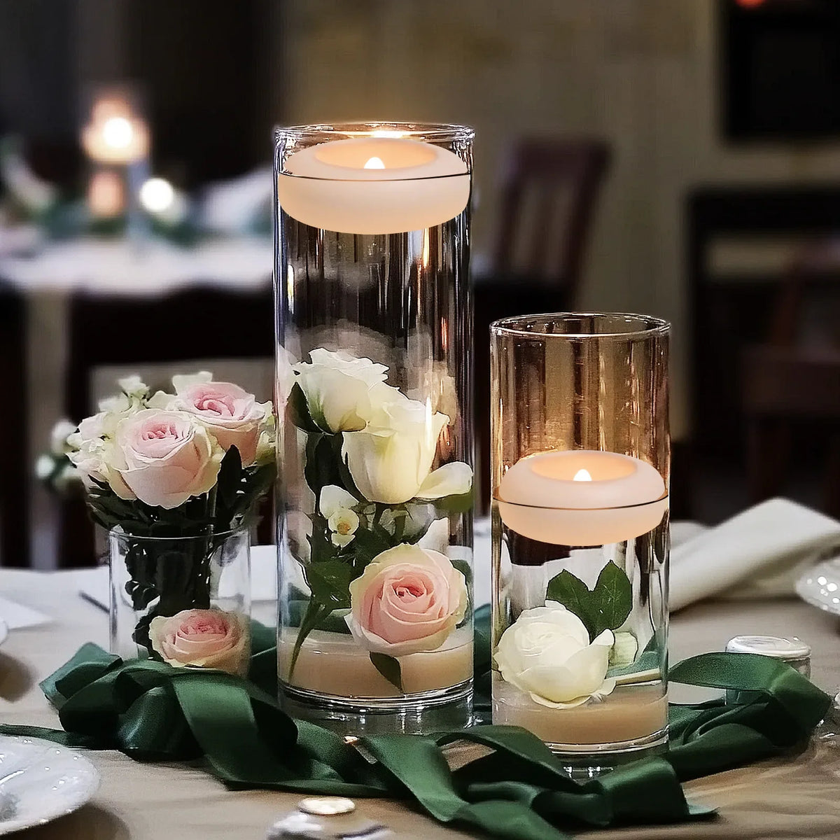 A glass vase holds several waterproof floating LED candles with a warm white glow on a table.