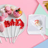 A display of various pink and red lollipops on paper sticks with tie closures, set against a light pink background.