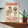 Vintage warning sign featuring cartoon figures of elderly people swimming, with text that reads Old People Swim Here Deal Wit