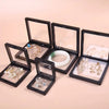 A set of black transparent floating display boxes for jewelry and collectibles, showing various rings and earrings.