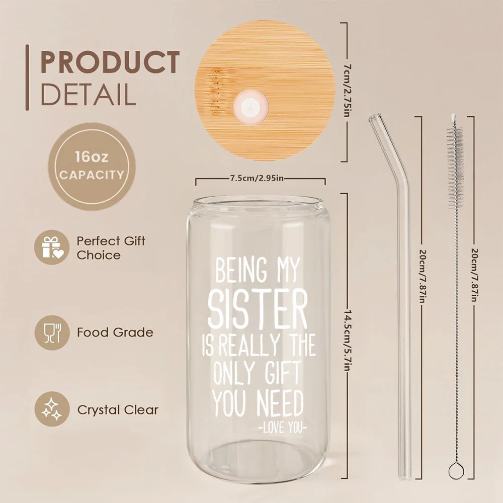 A clear glass tumbler with text engraved on it, shown next to a wooden lid and a cleaning brush.