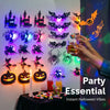 A hand is holding a glass of liquid in front of a display of glowing Halloween LED wall stickers and pumpkins.